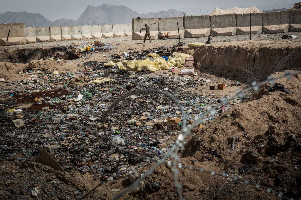 A soldier in the Afghan National Army (ANA) walks past a burn pit at a command outpost recently handed over to the ANA from the United States Army on March 22, 2013, in Kandahar Province, Zhari District, Afghanistan.