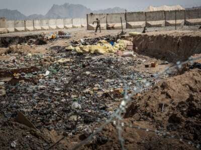 A soldier in the Afghan National Army (ANA) walks past a burn pit at a command outpost recently handed over to the ANA from the United States Army on March 22, 2013, in Kandahar Province, Zhari District, Afghanistan.