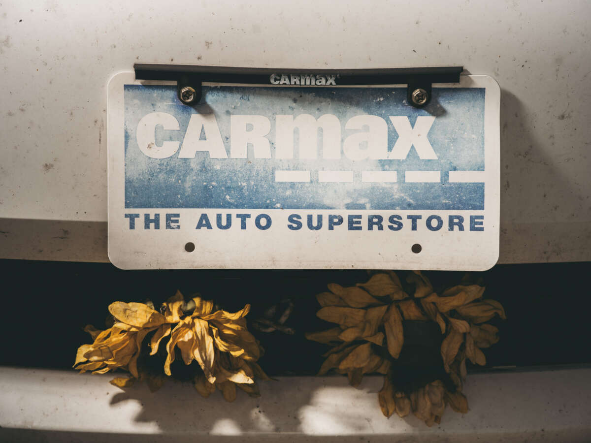 A faded Carmax plate on the front of Patterson’s car.