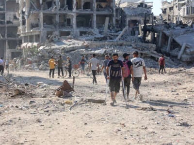 A Palestinian man on crutches walks on the dirt of a destroyed road past collapsed buildings after the Israeli military withdrew following a two-week offensive from the Shujaiya neighbourhood, east of Gaza City, on July 10, 2024.