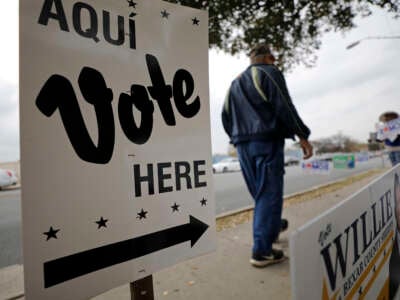 A pedestrian passes campaign signs outside a polling place on March 3, 2020, in San Antonio, Texas.