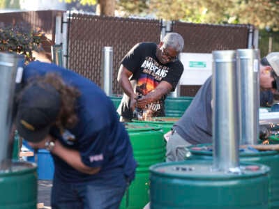 Boeing mechanic Clint Moore (center) works on making burn barrels in preparation to keep striking workers warm as votes are counted on a proposed contract between Boeing and union leaders and whether or not to strike if the contract is rejected, at the the Aerospace Machinists Union Hall in Seattle, Washington, on September 12, 2024.