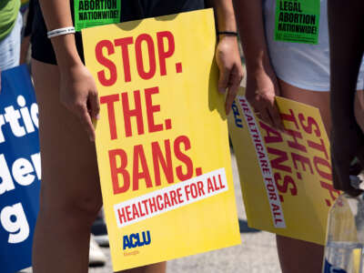 A protester holds a sign reading "STOP. THE. BANS." at an outdoor protest