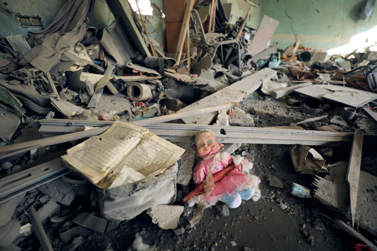 A battered doll is seen among rubble inside of a destroyed home