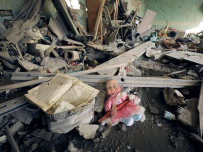 A battered doll is seen among rubble inside of a destroyed home