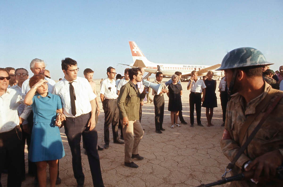 An Archival photo of people gathered on a tarmac near a grounded airplane