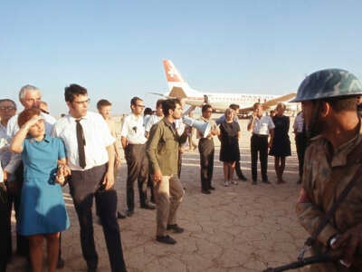 An Archival photo of people gathered on a tarmac near a grounded airplane