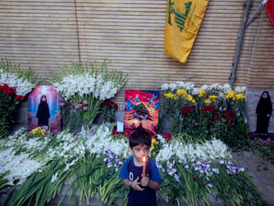 A boy holds a candle while standing in front of a memorial for a slain Lebanese girl