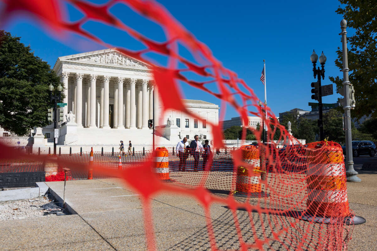 The SCOTUS building, as seen from behind a barrier of neon orange caution mesh