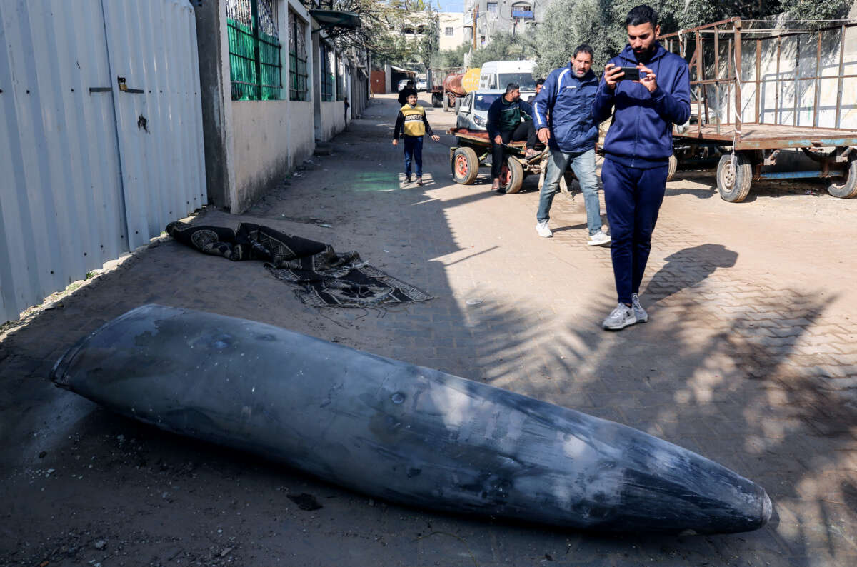 Palestinian people walk by an unexploded ordinance