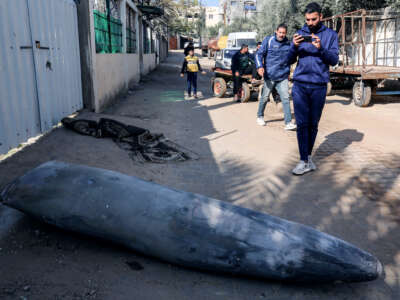 Palestinian people walk by an unexploded ordinance