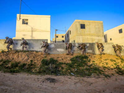 Marines maneuver along the side of a building at the National Training Center in Israel, March 13, 2018, during Juniper Cobra 2018, an exercise focused on U.S. European Command-Israel Defense Forces interoperability.