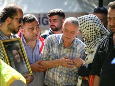 Mehmet Suat Eygi (center), father of late U.S.-Turkish activist Aysenur Ezgi Eygi shot dead by Israeli forces while protesting against illegal Israeli settlements in the occupied West Bank, mourns in front of a portrait of his daughter during her funeral ceremony at the cemetary in Didim, Aydin Province, on September 14, 2024.