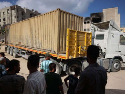 People stand next to a truck carrying 88 bodies, which according to the Palestinian health ministry entered the Gaza Strip from Israel the day before, as it awaits for the bodies to be unloaded and buried in a mass grave in Khan Yunis on September 26, 2024.