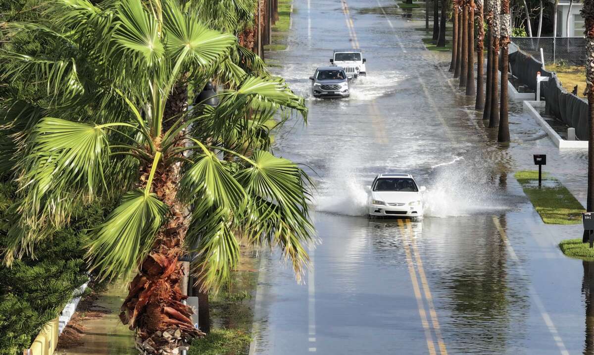 In this aerial view, vehicles drive through a flooded street as Hurricane Helene churns offshore on September 26, 2024, in St. Pete Beach, Florida.