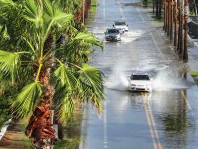 In this aerial view, vehicles drive through a flooded street as Hurricane Helene churns offshore on September 26, 2024, in St. Pete Beach, Florida.