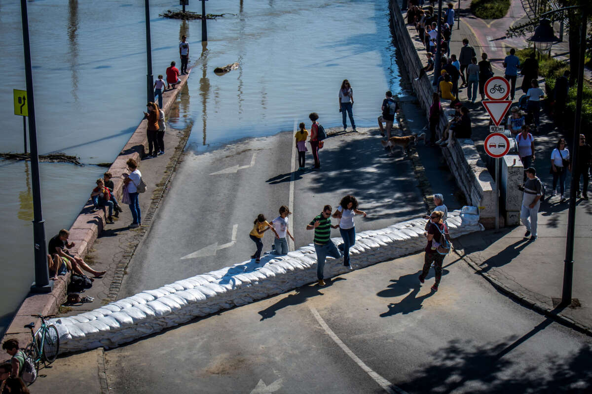 Onlookers walk over a barrier made of sandbags set up for protection against floodwater as the Danube floods the river bank in Budapest, Hungary, on September 21, 2024, reaching its peak and marking a 10-year high, after deadly storm Boris lashed Europe.