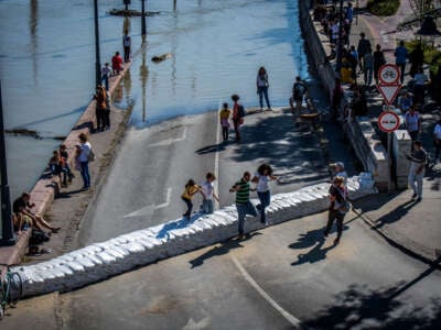 Onlookers walk over a barrier made of sandbags set up for protection against floodwater as the Danube floods the river bank in Budapest, Hungary, on September 21, 2024, reaching its peak and marking a 10-year high, after deadly storm Boris lashed Europe.