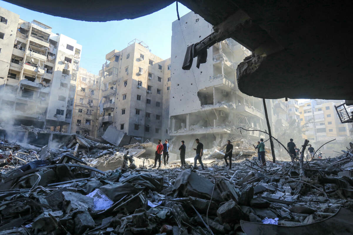 People walk amid the rubble of an apartment complex in Lebanon destroyed by Israel