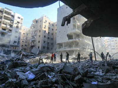 People walk amid the rubble of an apartment complex in Lebanon destroyed by Israel