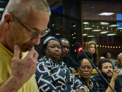 Mia Perez, center-left, a Haitian-Cuban-American translator and attorney from Springfield, Ohio, and business leaders in the town's growing Haitian community, listen as an area resident denounces the town's growing Haitian population during a town hall meeting on September 24, 2024.