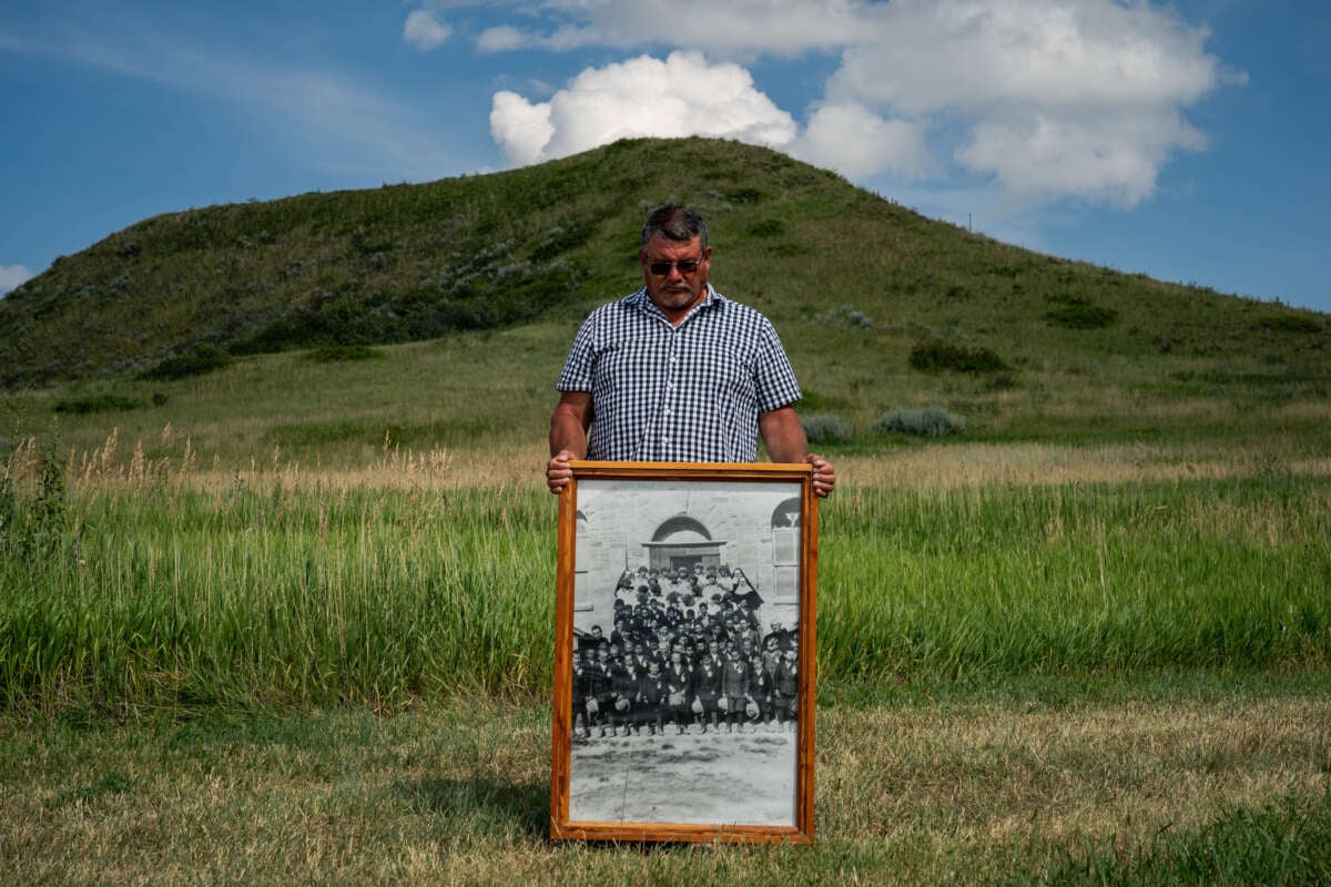 Warren Morin, 59, a member of Gros Ventre and Assiniboine tribes, holds a framed photo of his grandfather and other family members attending St. Paul's Mission boarding school as children on the Fort Belknap Reservation in Lodge Pole, Montana, on July 12, 2023.