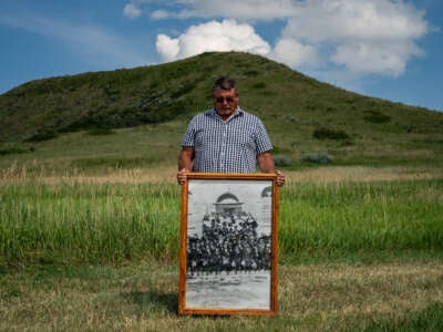 Warren Morin, 59, a member of Gros Ventre and Assiniboine tribes, holds a framed photo of his grandfather and other family members attending St. Paul's Mission boarding school as children on the Fort Belknap Reservation in Lodge Pole, Montana, on July 12, 2023.