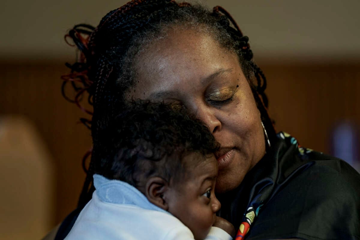 Hajime White, exhausted from planning and executing a ceremony for mothers and their young children, snuggles with her grandson at the Warren Housing Authority on March 23, 2024, in Warren, Arkansas. Arkansas had the highest known rate of maternal mortality in the U.S. from 2018 to 2020, according to the CDC. Hajime White is one of the state's few Black doulas who works to help moms/babies in her area.