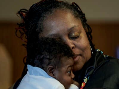 Hajime White, exhausted from planning and executing a ceremony for mothers and their young children, snuggles with her grandson at the Warren Housing Authority on March 23, 2024, in Warren, Arkansas. Arkansas had the highest known rate of maternal mortality in the U.S. from 2018 to 2020, according to the CDC. Hajime White is one of the state's few Black doulas who works to help moms/babies in her area.