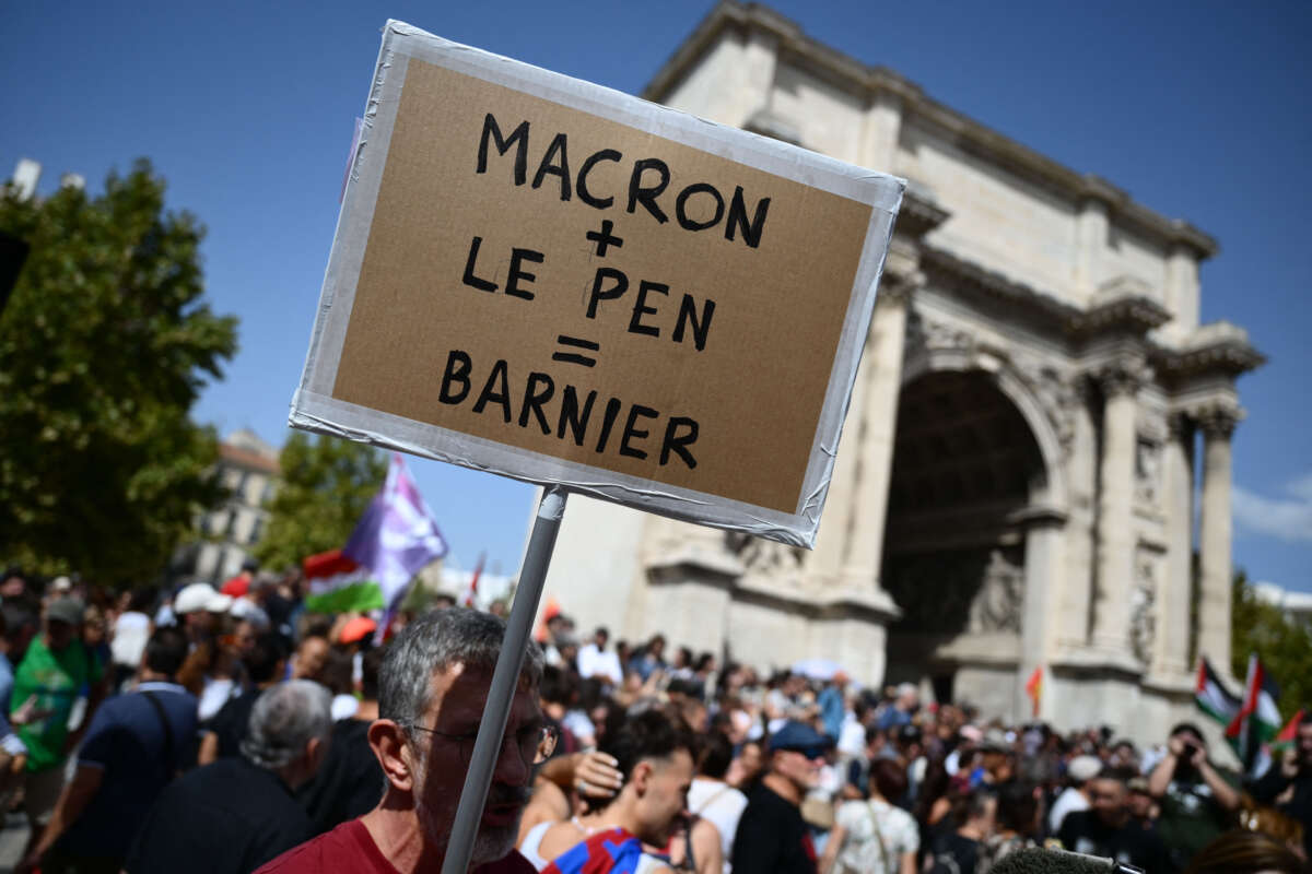 A demonstrator holds placard reading "Macron + Le Pen = Barnier" in a demonstration against the appointment of right-wing Prime Minister Michel Barnier by France's President Emmanuel Macron in Marseille, France, on September 7, 2024.