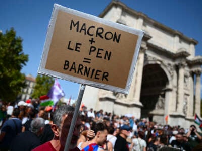 A demonstrator holds placard reading "Macron + Le Pen = Barnier" in a demonstration against the appointment of right-wing Prime Minister Michel Barnier by France's President Emmanuel Macron in Marseille, France, on September 7, 2024.