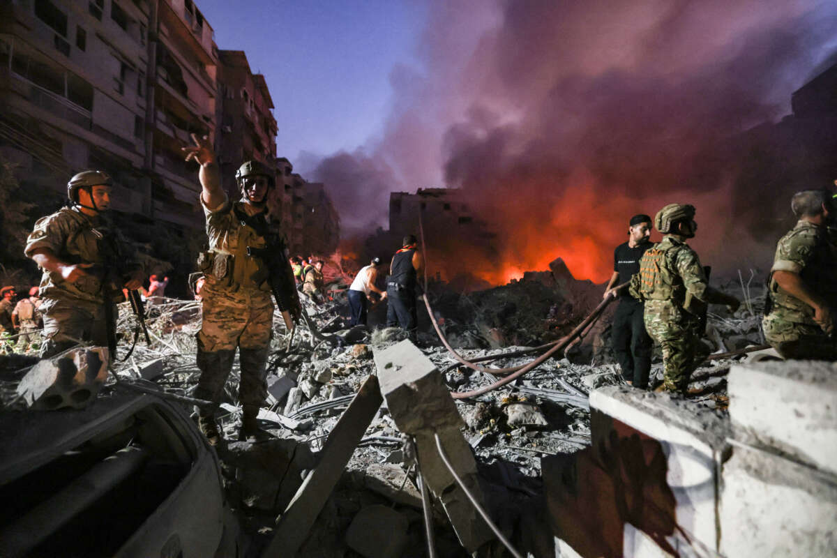 Lebanese army soldiers gather over the rubble of a leveled building as people flight the flames, following Israeli air strikes in the Haret Hreik neighbourhood of Beirut's southern suburbs, on September 27, 2024.