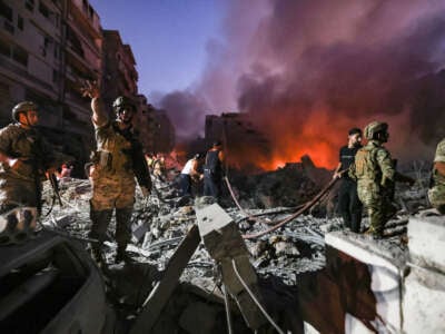 Lebanese army soldiers gather over the rubble of a leveled building as people flight the flames, following Israeli air strikes in the Haret Hreik neighbourhood of Beirut's southern suburbs, on September 27, 2024.