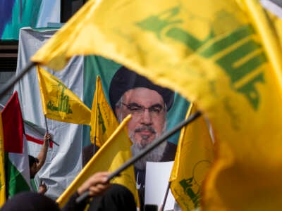 Iranians wave Lebanon's Hezbollah flags in front of a portrait of the Hezbollah Secretary General, Hassan Nasrallah, during a protest to condemn Israel's military attack on Lebanon, after Friday prayers ceremonies in downtown Tehran, Iran, on September 27, 2024.