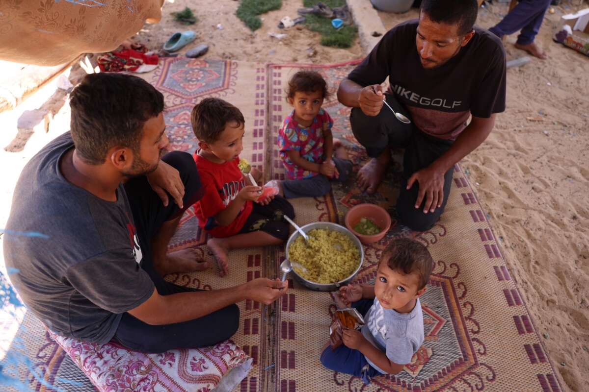 Displaced Palestinians sit for a meal at a makeshift camp for the displaced in Khan Yunis in the southern Gaza Strip on September 11, 2024.