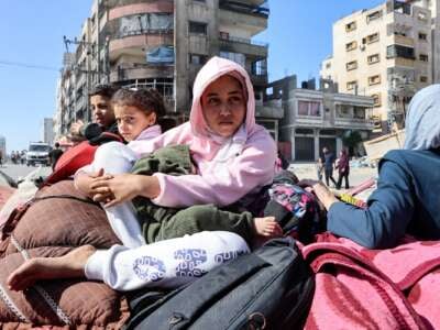 Palestinian children sit atop their family's belongings as they flee areas north of Gaza City in the northern Gaza Strip on October 12, 2024.