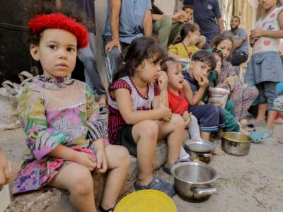 Displaced Palestinians queue to receive food rations, offered by a charity, in Gaza's refuge at Nuseirat refugee camp on October 18, 2024.