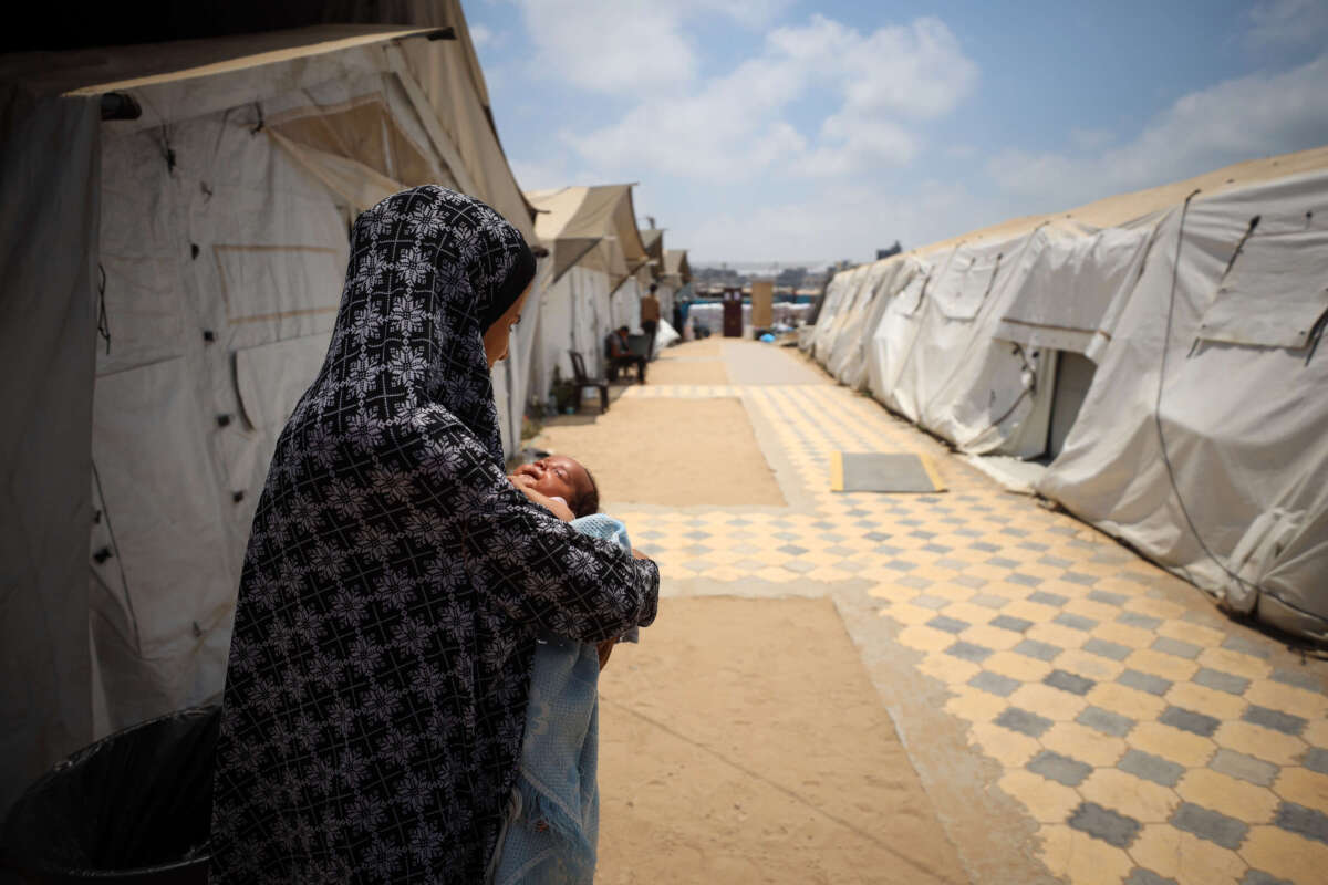 A displaced Palestinian mother holds her baby at the International Medical Corps field hospital in Deir Al-Balah, in the southern Gaza Strip, on July 22, 2024.