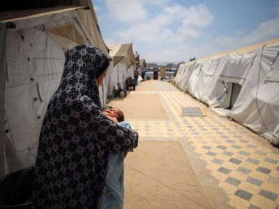 A displaced Palestinian mother holds her baby at the International Medical Corps field hospital in Deir Al-Balah, in the southern Gaza Strip, on July 22, 2024.