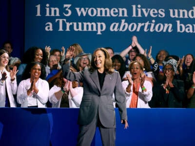 Kamala Harris waves as women seated behind her applaud