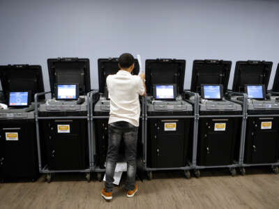 A man with stands at an electric voting machine