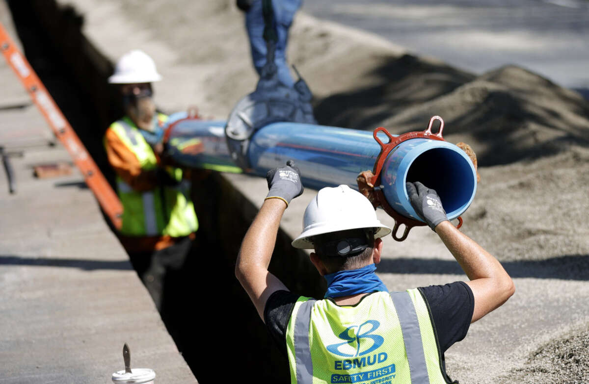 Workers with East Bay Municipal Utility District install new water pipe on April 22, 2021, in Walnut Creek, California.