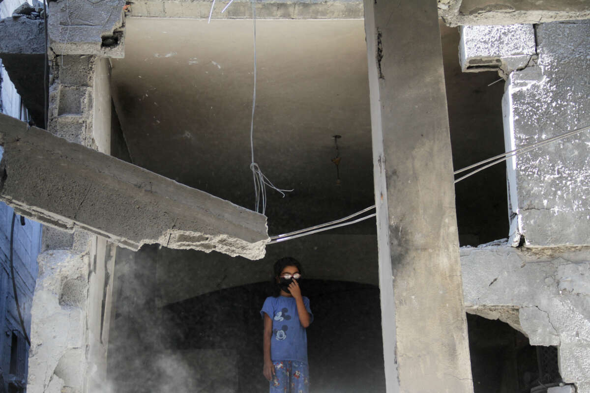 A girl in glasses stands in a destroyed building