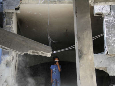 A girl in glasses stands in a destroyed building