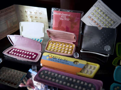 Various brands of birth control pills are displayed for a photo