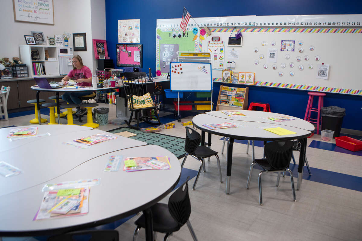 An educator sits in an empty classroom