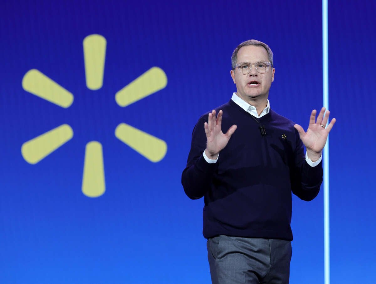 Walmart President in front of the walmart logo