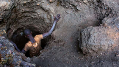 A man descends into a tiny hole in the ground