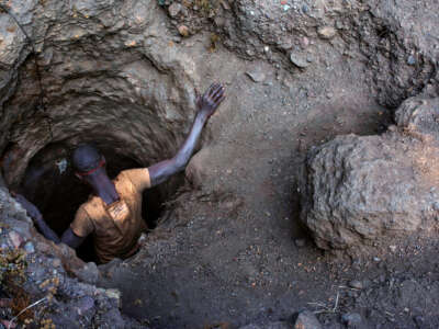 A man descends into a tiny hole in the ground