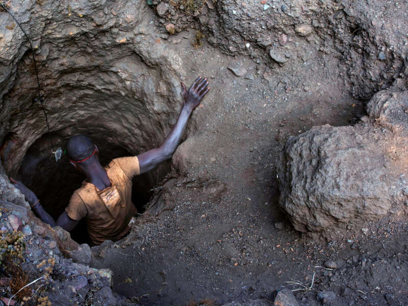 A man descends into a tiny hole in the ground